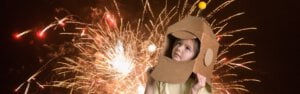 kind met kartonne helm kijkt naar vuurwerk