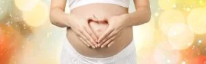 zwangere moeder met handen in vorm van hart op haar buik